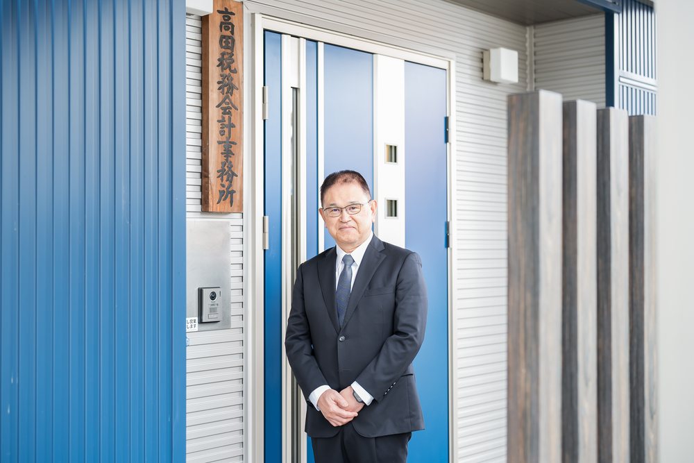 事務所の入口に立つ所長 高田雅信